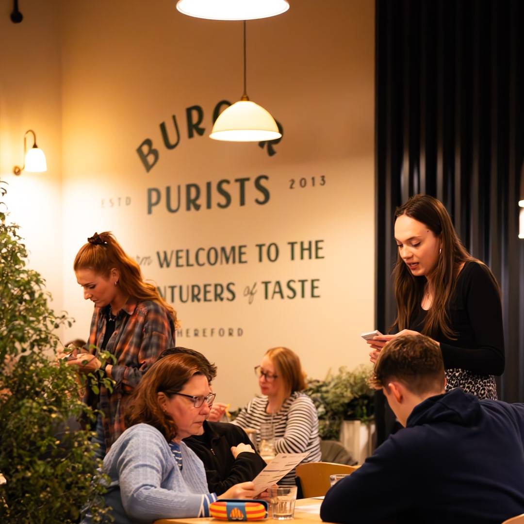 People enjoying the delicious burger from Burger Shop Hereford London, showcasing fresh ingredients and a perfectly toasted bun.